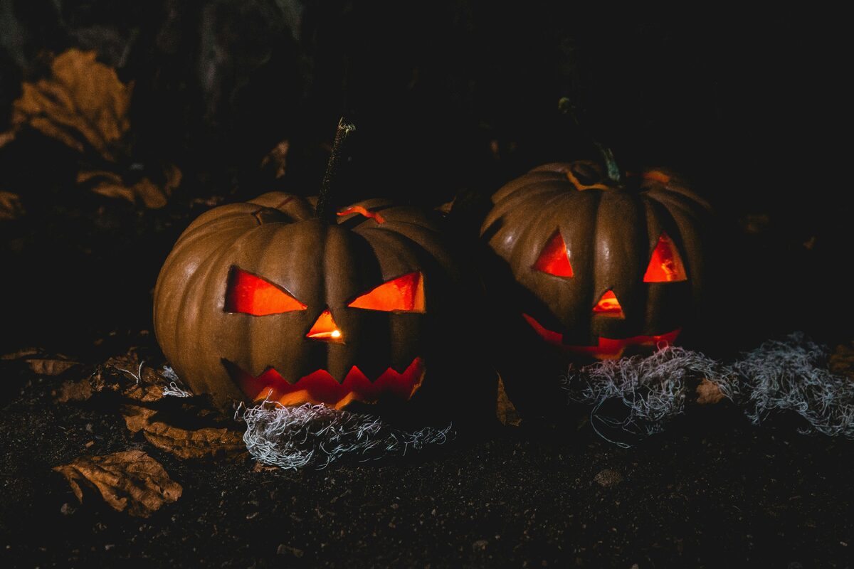 Two eerie jack-o'-lanterns with glowing eyes and spooky expressions illuminating the dark night.